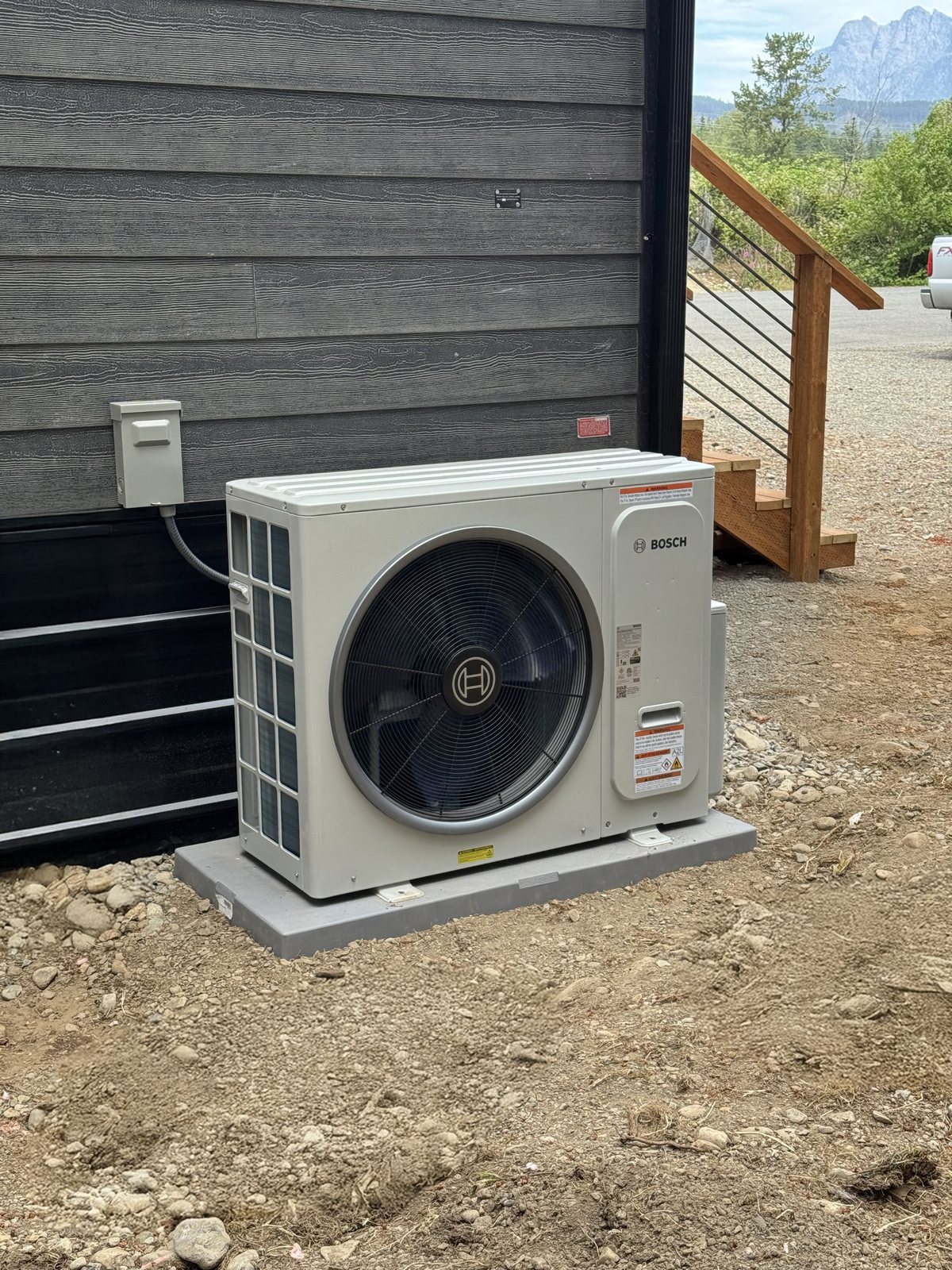 New outdoor AC condenser unit installed on a composite pad beside a home
